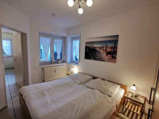 Helles Schlafzimmer mit Doppelbett, Fenster und einem Bild von einem Strand.