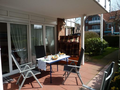 Balkon mit Tisch, Stühlen und gedecktem Frühstück, umgeben von grüner Landschaft.
