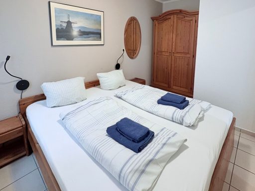 Helle, gemütliche Schlafzimmer mit zwei Einzelbetten, Nachttischen und Holzschrank.