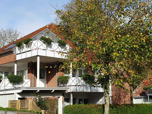 Zweifamilienhaus mit Balkonen, umgeben von Bäumen und grüner Hecke.