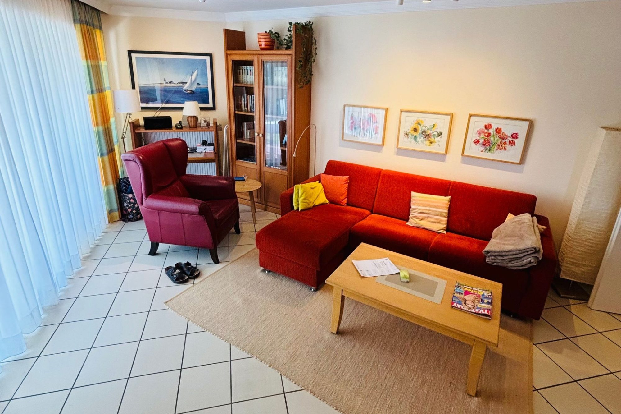 Heller Wohnraum mit rotem Sofa, Holztisch und TV-Schrank, dekoriert mit Bildern.