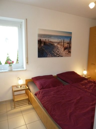 Helles Schlafzimmer mit zwei Betten, Tisch und Landschaftsbild an der Wand.