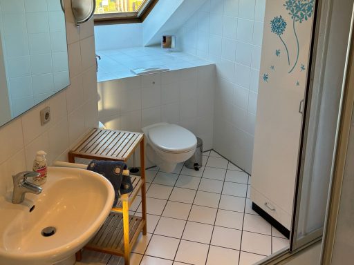 Helles Badezimmer mit Waschbecken, Toilette und Schrank, Fenster mit Tageslicht.