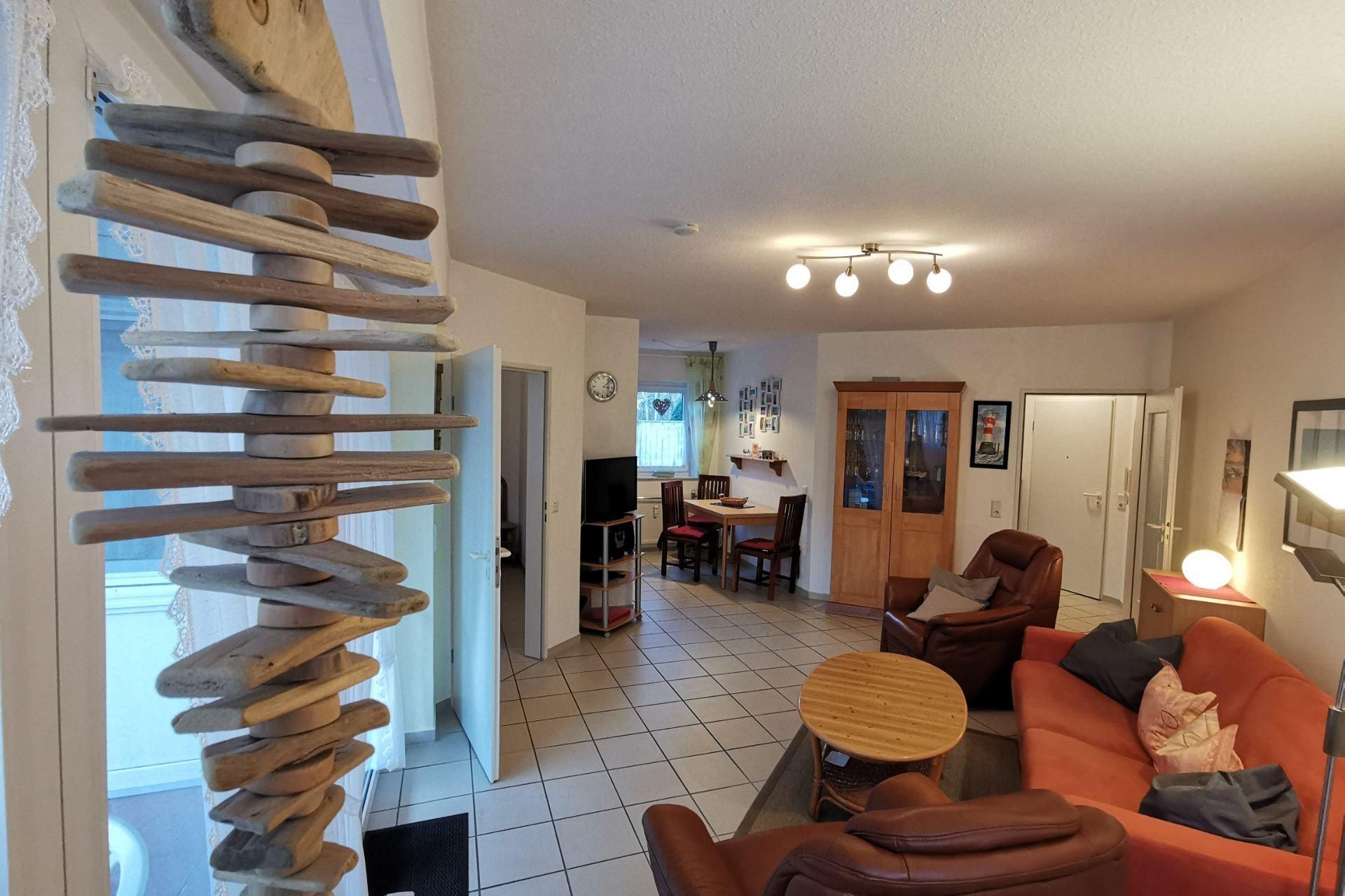 Wohnzimmer mit rotem Sofa, zwei Sesseln und Kaffeetisch, hellen Wänden und Bildern.