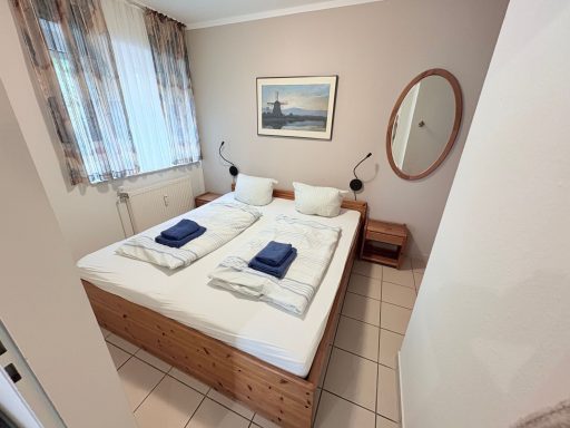 Doppelzimmer mit zwei Betten, Nachttisch und Fenster mit Vorhängen.