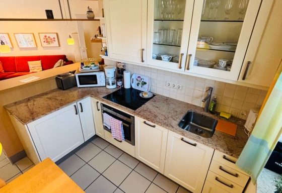 Helle Küche mit modernem Design, Herd, Spüle und verschiedenen Geräten.