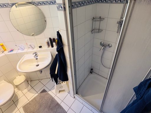 Badezimmer mit Dusche, Waschbecken, WC und blauen Handtüchern.