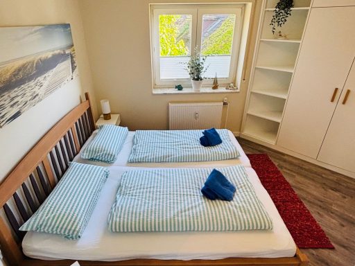 Helles Schlafzimmer mit zwei Betten, blauen Handtüchern und Regal im Hintergrund.