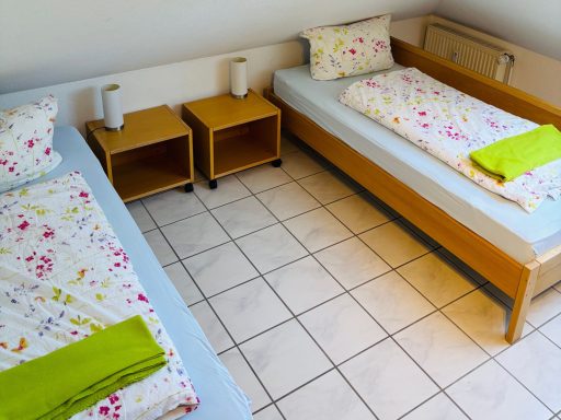 Zwei Einzelbetten mit bunten Bettwäsche und Handtüchern in einem hellen Raum.