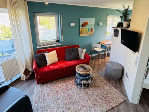 Heller Wohnraum mit roter Couch, Tisch, Stühlen und moderner Dekoration.