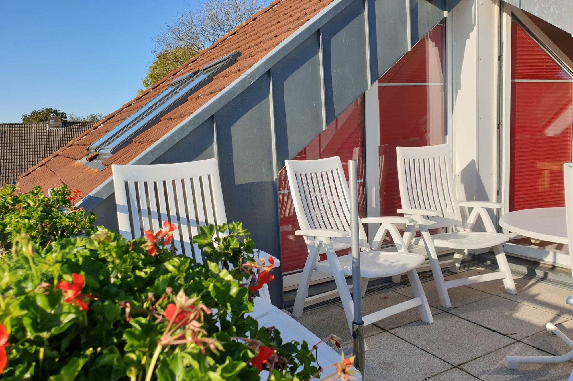 Wohnzimmer mit modernen Möbeln, Fenster mit Dachschrägen und TV auf einem Regal.